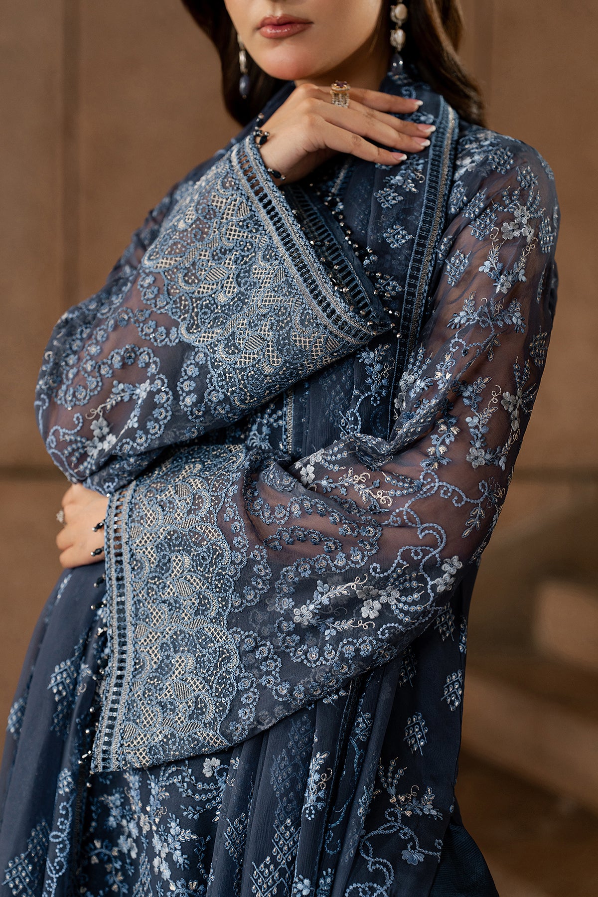 Woman wearing a dark blue embroidered dress with a brown background