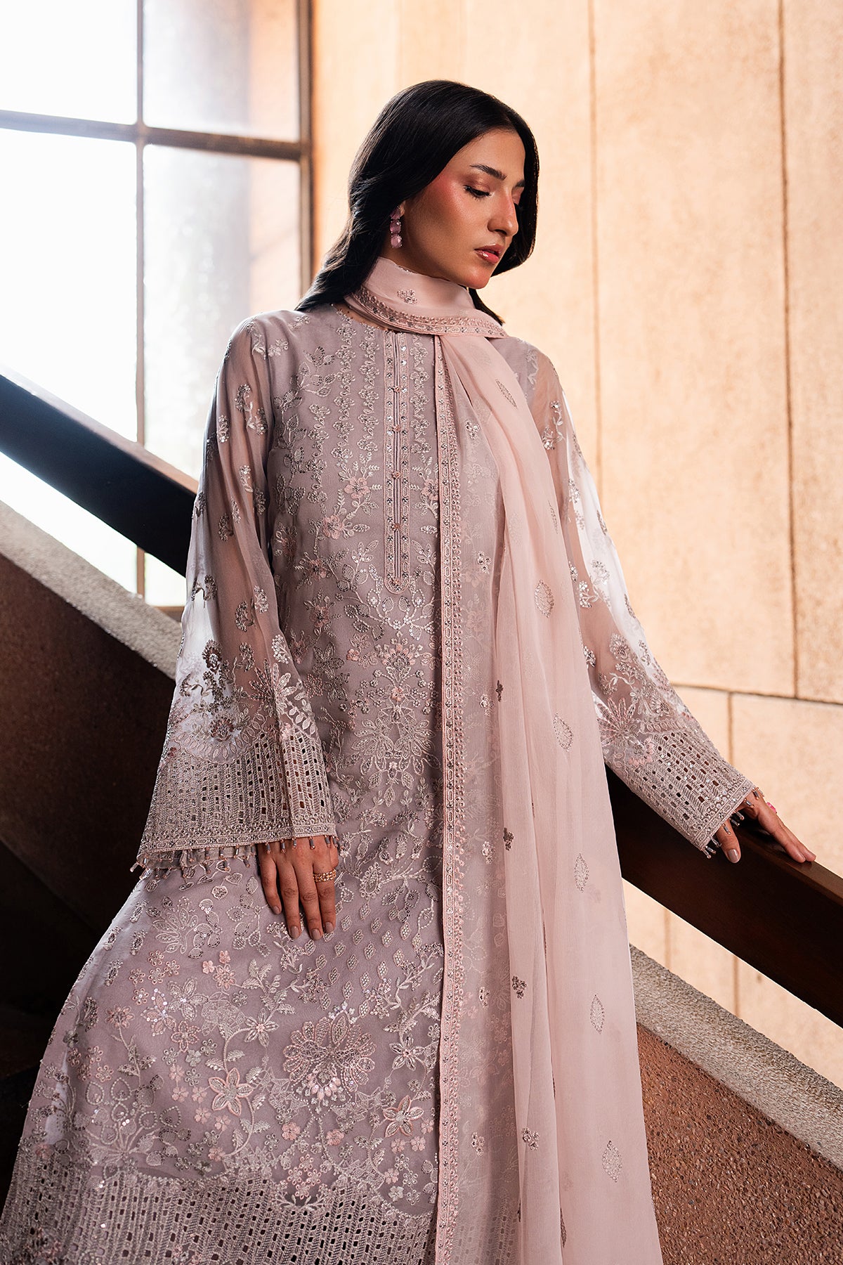 Woman wearing a light purple embroidered outfit with a sheer dupatta in an indoor setting.