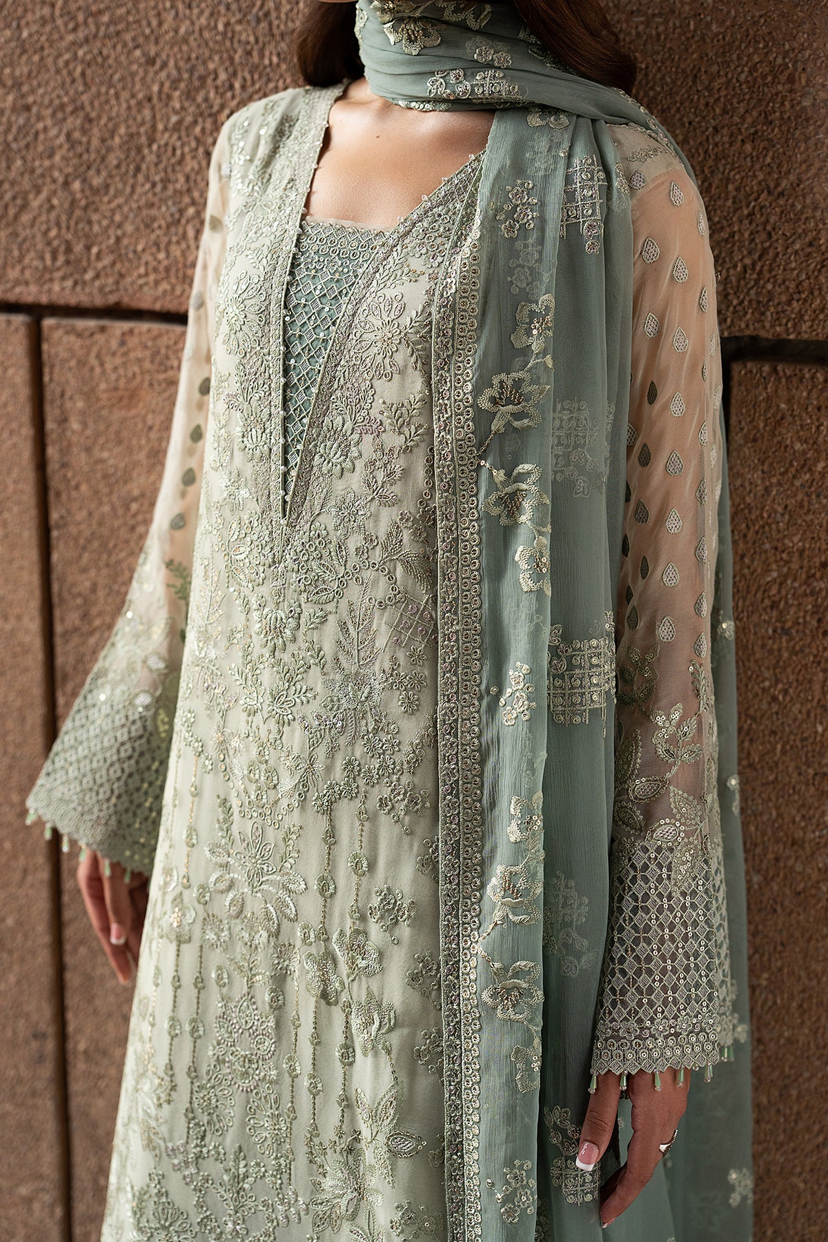 Light green embroidered traditional outfit with a matching dupatta against a brown background