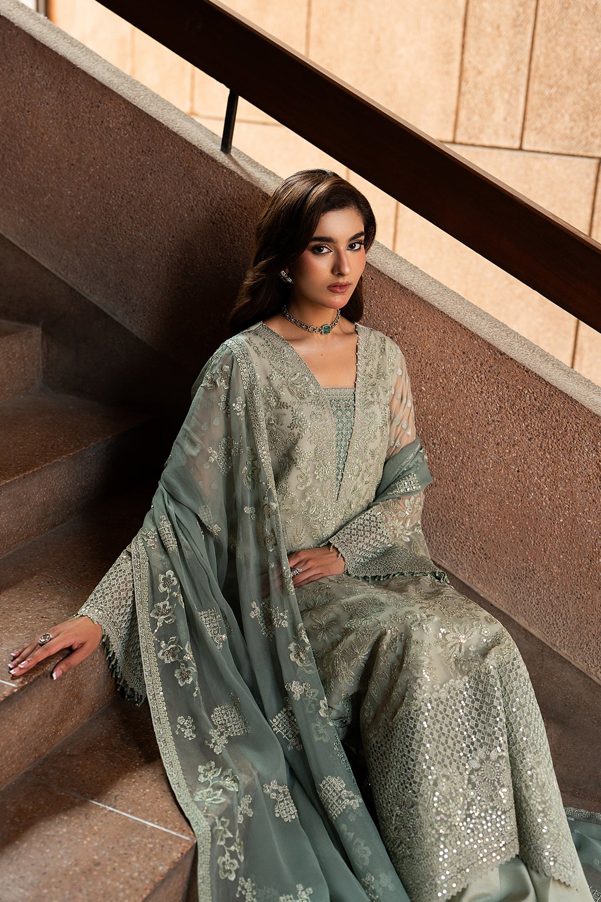 Woman in a light green traditional outfit sitting on a staircase.