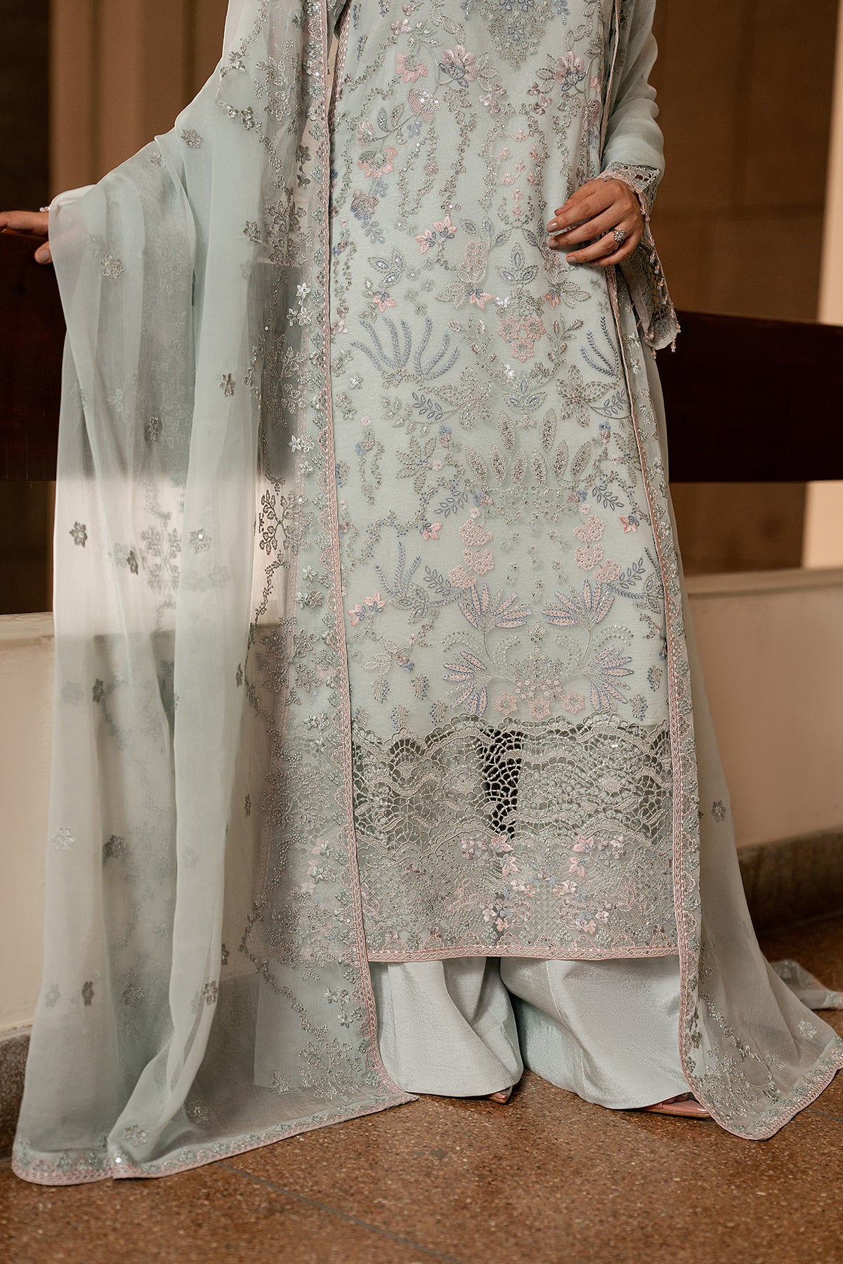 Traditional outfit with floral embroidery and a sheer dupatta on a neutral background